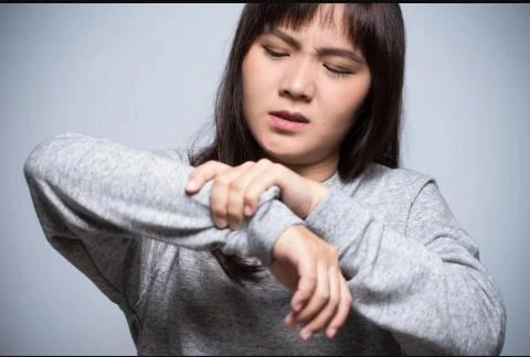 Person wincing while holding their own wrist in pain